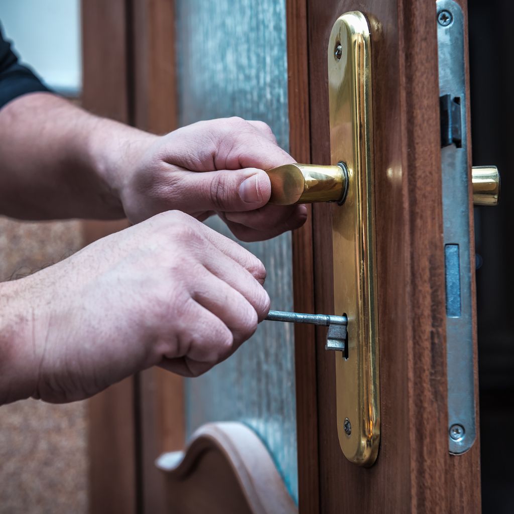 Hand draait een sleutel in een messing cilinderslot van een houten voordeur.