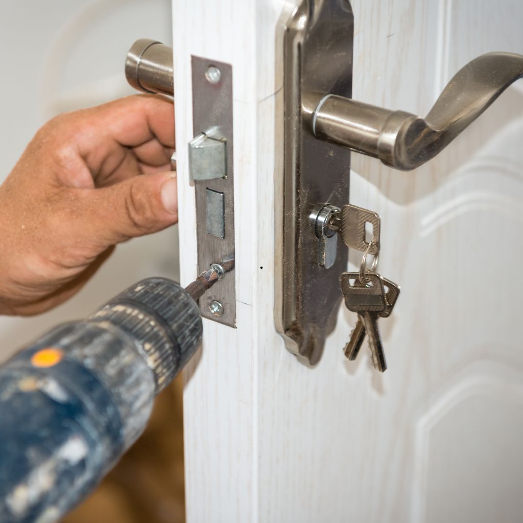 Monteur bevestigt een insteekslot in een witte deur met een accuboormachine.