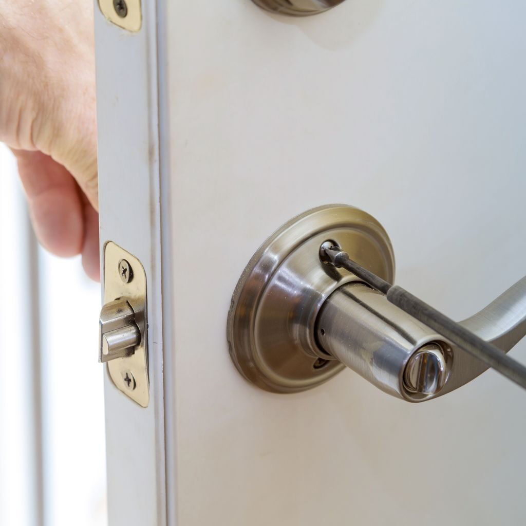 Slotenmaker die een deurklink en slot repareert met een schroevendraaier