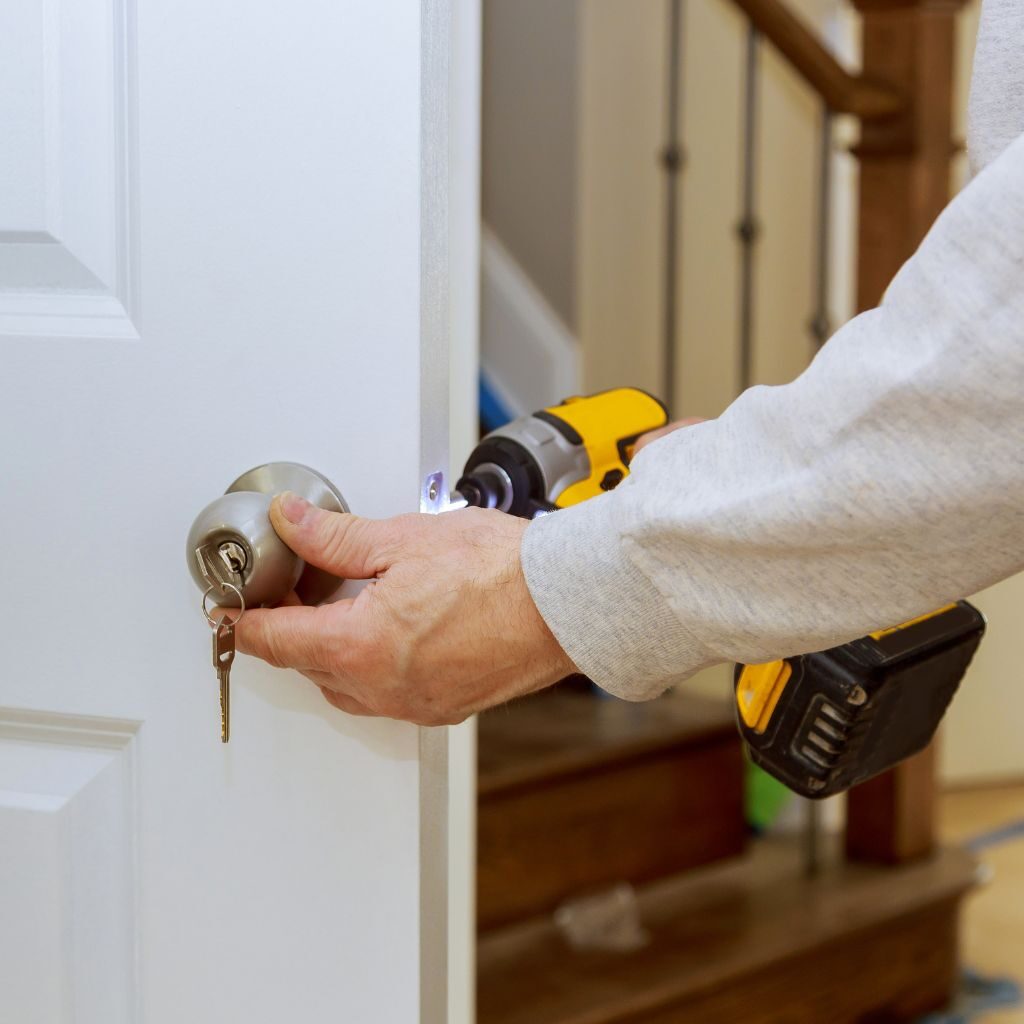 Monteur installeert een deurslot met elektrisch gereedschap